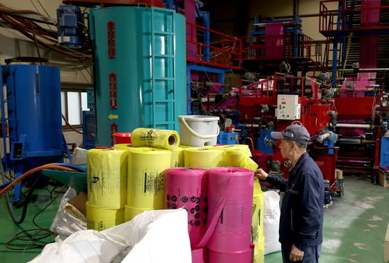 A worker inspects standardized garbage bags produced using recycled raw materials processed from vinyl instead of naphtha at a factory in Changwon, South Gyeongsang, on the morning of April 9. [YONHAP]