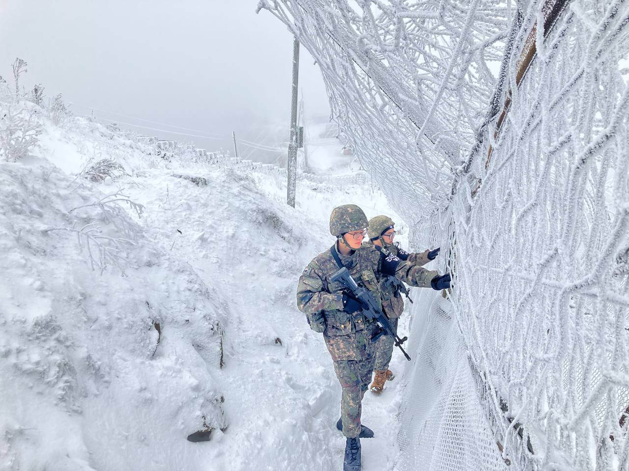 On Dec. 12, 2023, soldiers of the Army’s 21st Division stand guard while carefully inspecting a snow-covered barbed-wire fence at a general outpost. At Gachilbong, an observation post at an elevation of 1,242 meters (4,074 feet)) — the highest in the Army — 11 centimeters (4.33 inches) of snow fell overnight. [MINISTRY OF NATIONAL DEFENSE/NEWS1]