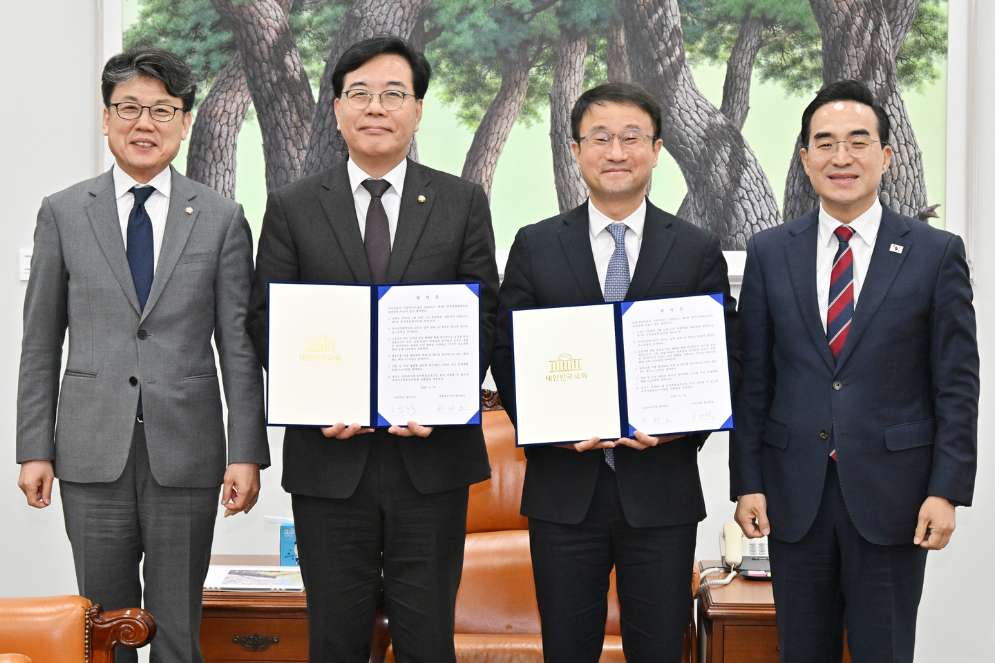 Han Byung-do, center right, floor leader of the ruling Democratic Party, poses for a commemorative photo with main opposition People Power Party floor leader Song Eon-seog, center left, after agreeing to pass a supplementary budget bill to responds to the economic fallout from the Middle East war at the National Assembly in western Seoul on April 10. [JOINT PRESS CORPS]