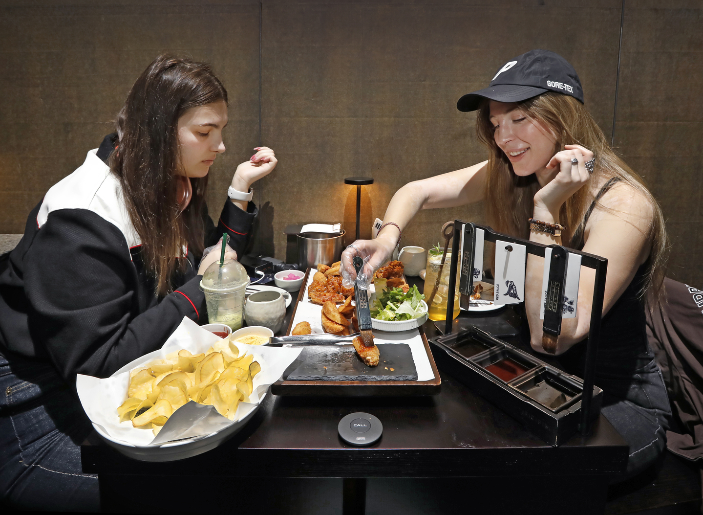 Alina Kasatkina, right, a tourist from Russia, brushes sauce onto her chicken at Kyochon Pilbang, the flagship store of one of Korea's biggest chicken franchises, in Itaewon, central Seoul, on April 7. [PARK SANG-MOON] 