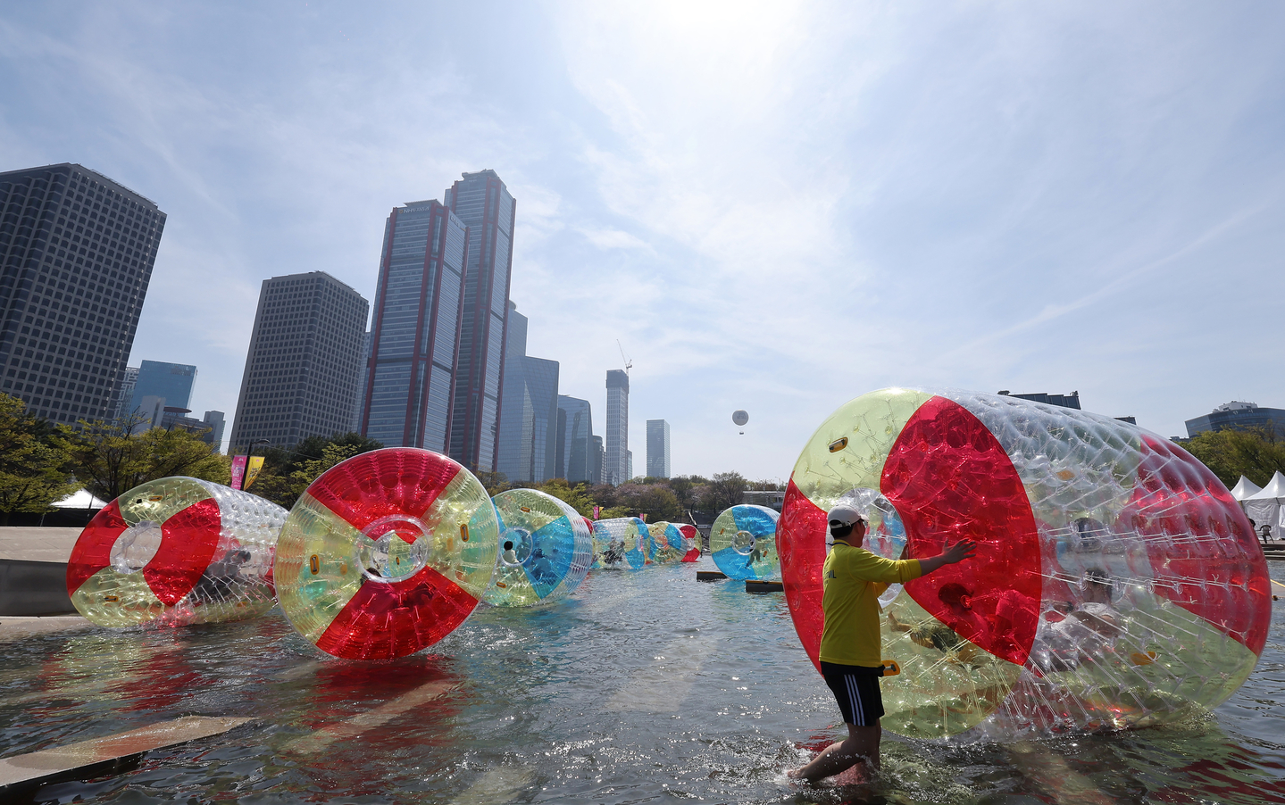 Visitors push giant inflatable water balls during the Seoul Spring Festival at Yeouido Hangang Park in Yeongdeungpo District, western Seoul, on April 12. Running through May 5 across parks along the Han River, the event also features attractions such as a floating carousel and a treasure hunt. [NEWS1] 
