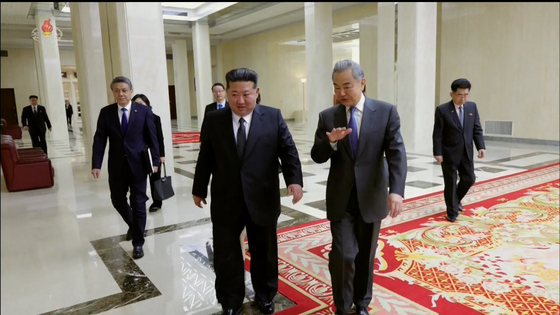 Kim Jong-un, left, walks with Chinese Foreign Minister Wang Yi during the minister's visit to Pyongyang on April 10, in this screenshot from a video released by the Korean Central Television. [YONHAP] 