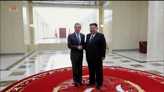 Kim Jong-un, right, shakes hands with Chinese Foreign Minister Wang Yi during the minister's visit to Pyongyang on April 10, in this screenshot from a video released by the Korean Central Television. [YONHAP] 