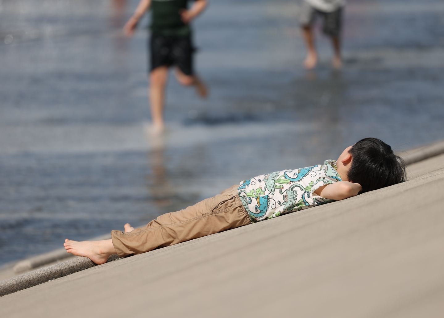 A child is seen lying on near a pool-like facility in Yeouido, western Seoul, on April 12. [YONHAP] 