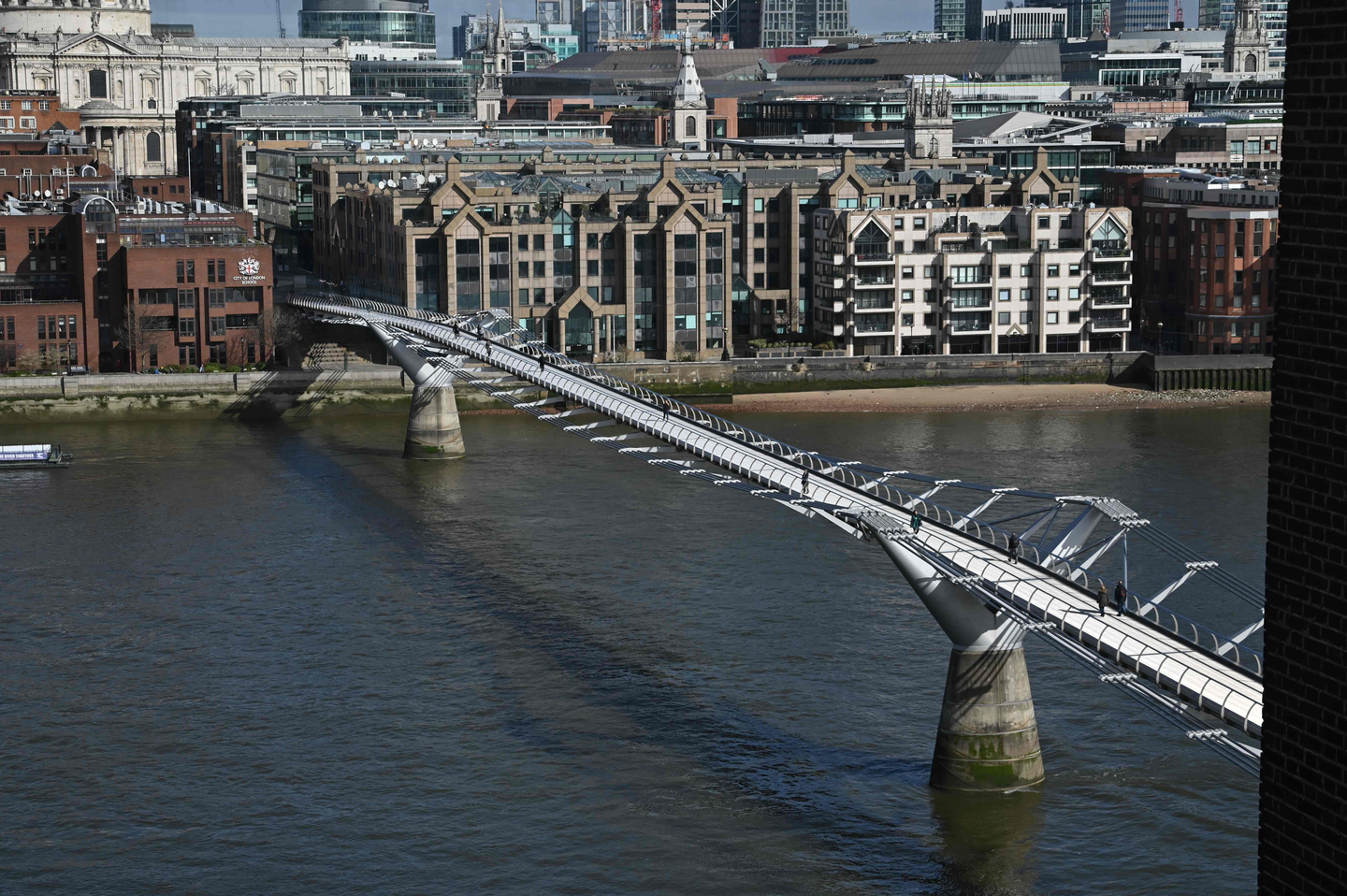 Pedestrians cross the Millennium Footbridge across the River Thames in London on March 17, 2020. [AFP/YONHAP]