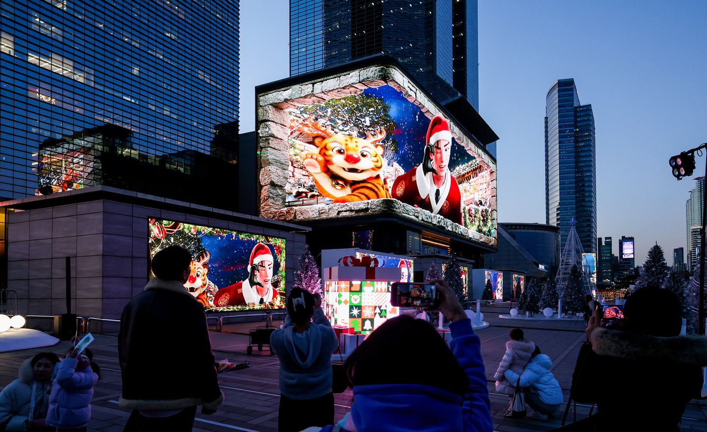 People watch a digital billboard display a Christmas-themed video featuring the city mascot, Hechi, during the 2025 Gangnam Media Winter Festa near Samseong Station in southern Seoul on Dec. 22, 2025. [WOO SANG-JO]