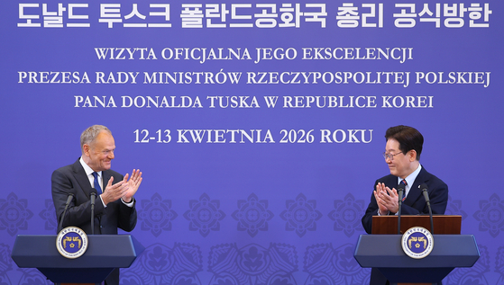 President Lee Jae Myung, right, and Polish Prime Minister Donald Tusk clap as they hold a joint press briefing at the Blue House in central Seoul on April 13. [JOINT PRESS CORPS]