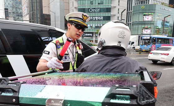 A police officer talks to a motorbike rider in Gangnam District, southern Seoul, on July 15, 2025. [YONHAP]