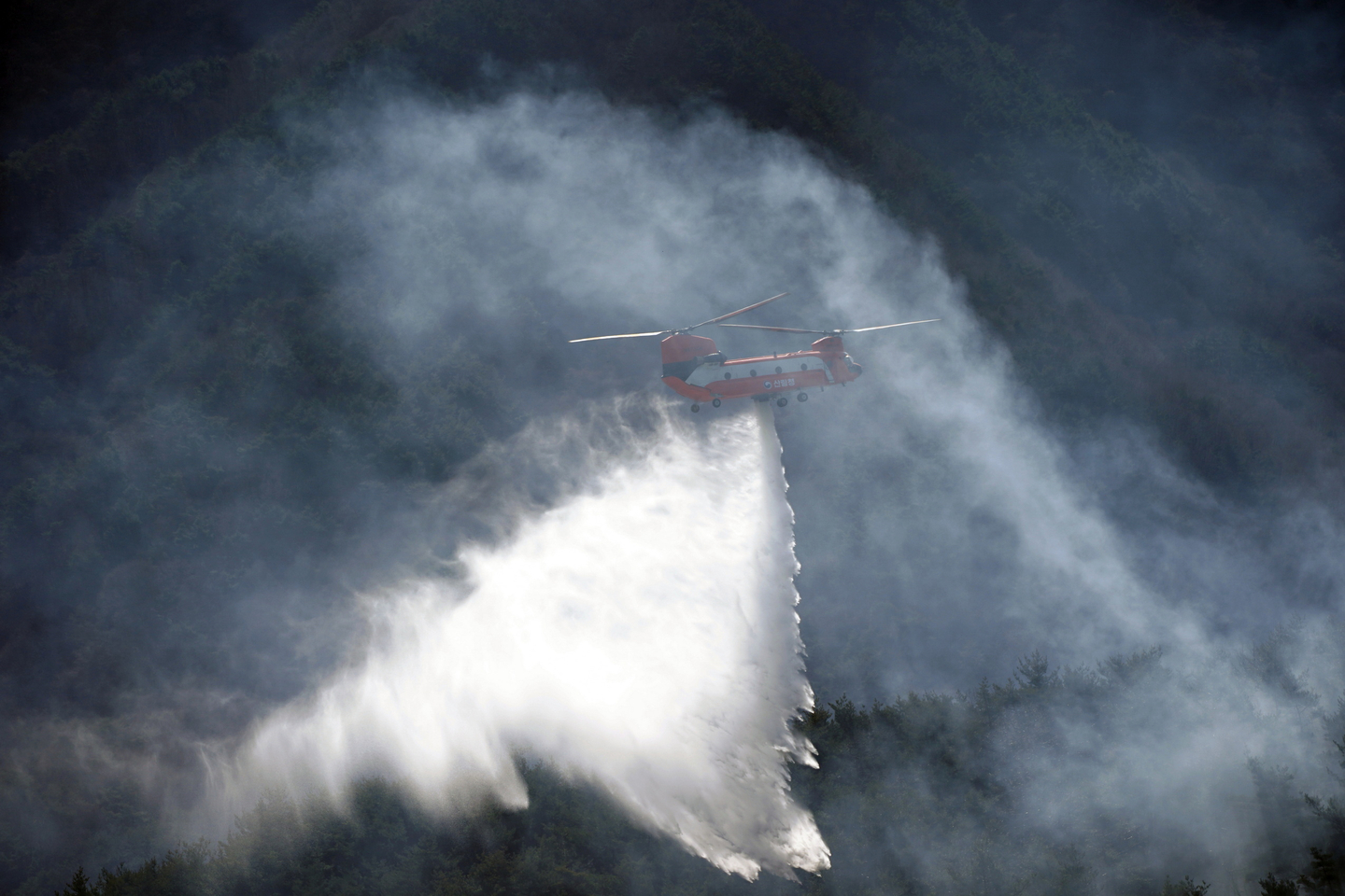 A forestry helicopter conducts wildfire suppression operations in Hamyang County, South Gyeongsang on Feb. 23. [YONHAP]