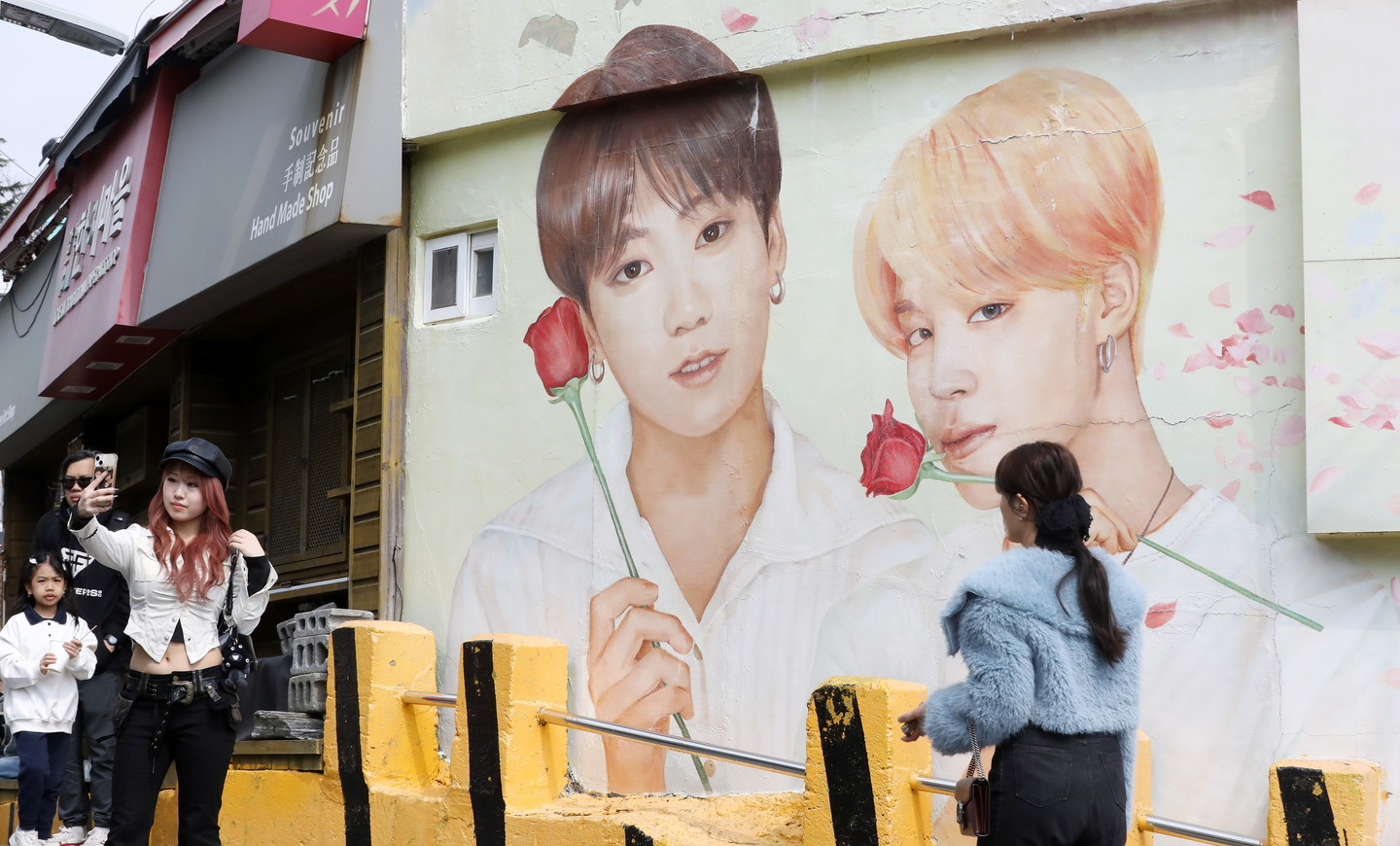 People take photos in front of a large mural of BTS members Jungkook and Jimin, both Busan-born, at Gamcheon Culture Village in Busan on March 19. [NEWS1]