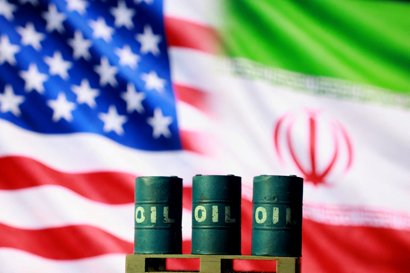 U.S. and Iranian flags are seen behind oil barrels in this illustration created on March 23. [REUTERS/YONHAP]