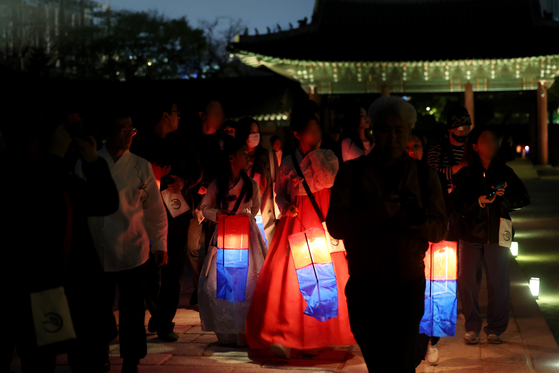 Participants of the Changdeok Palace's Moonlight Tour walks inside the palace sites on April 14 holding traditional lanterns. [YONHAP]