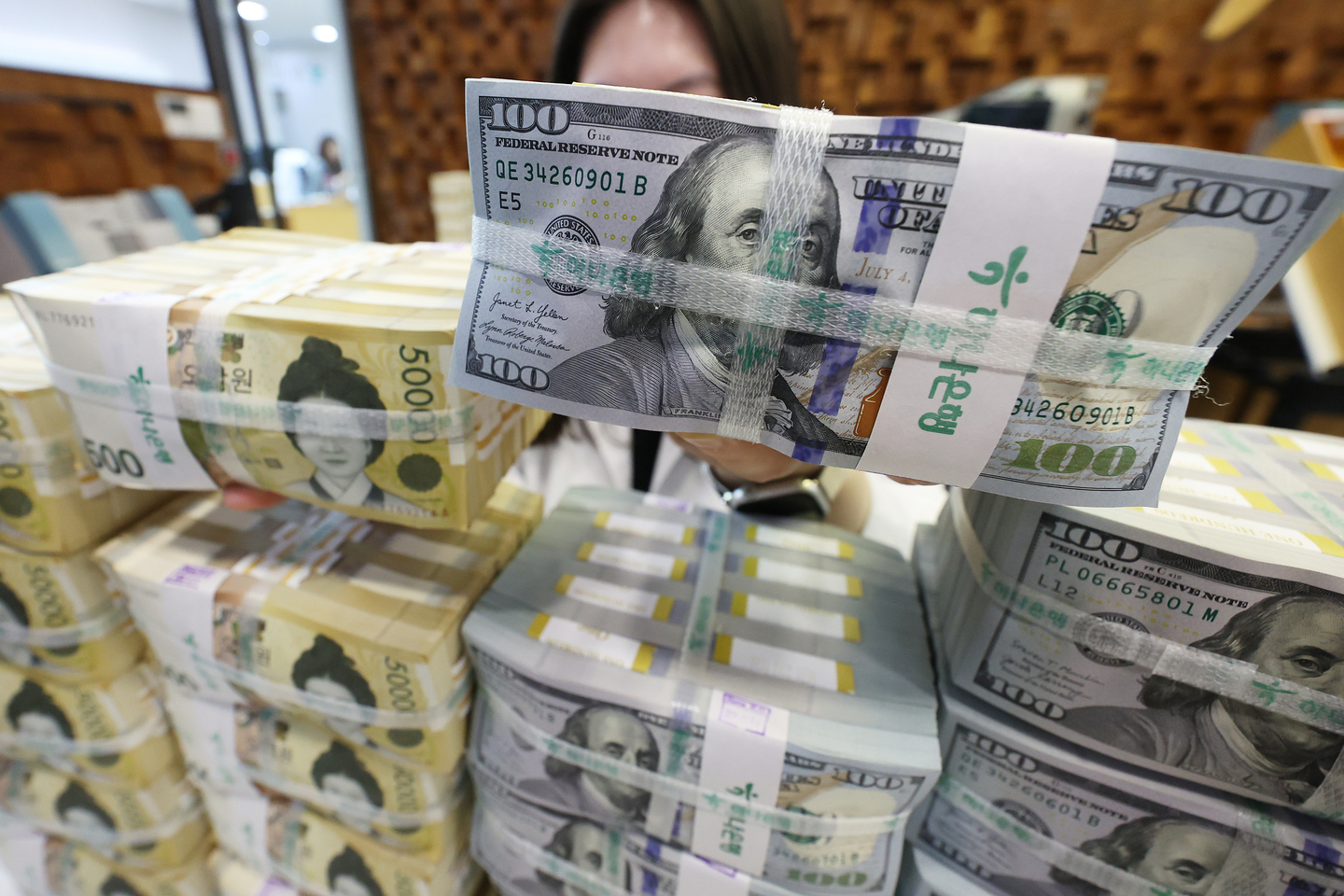 Bundles of U.S. dollars and Korean won are piled up in at Hana Bank in central Seoul in April. [YONHAP]  