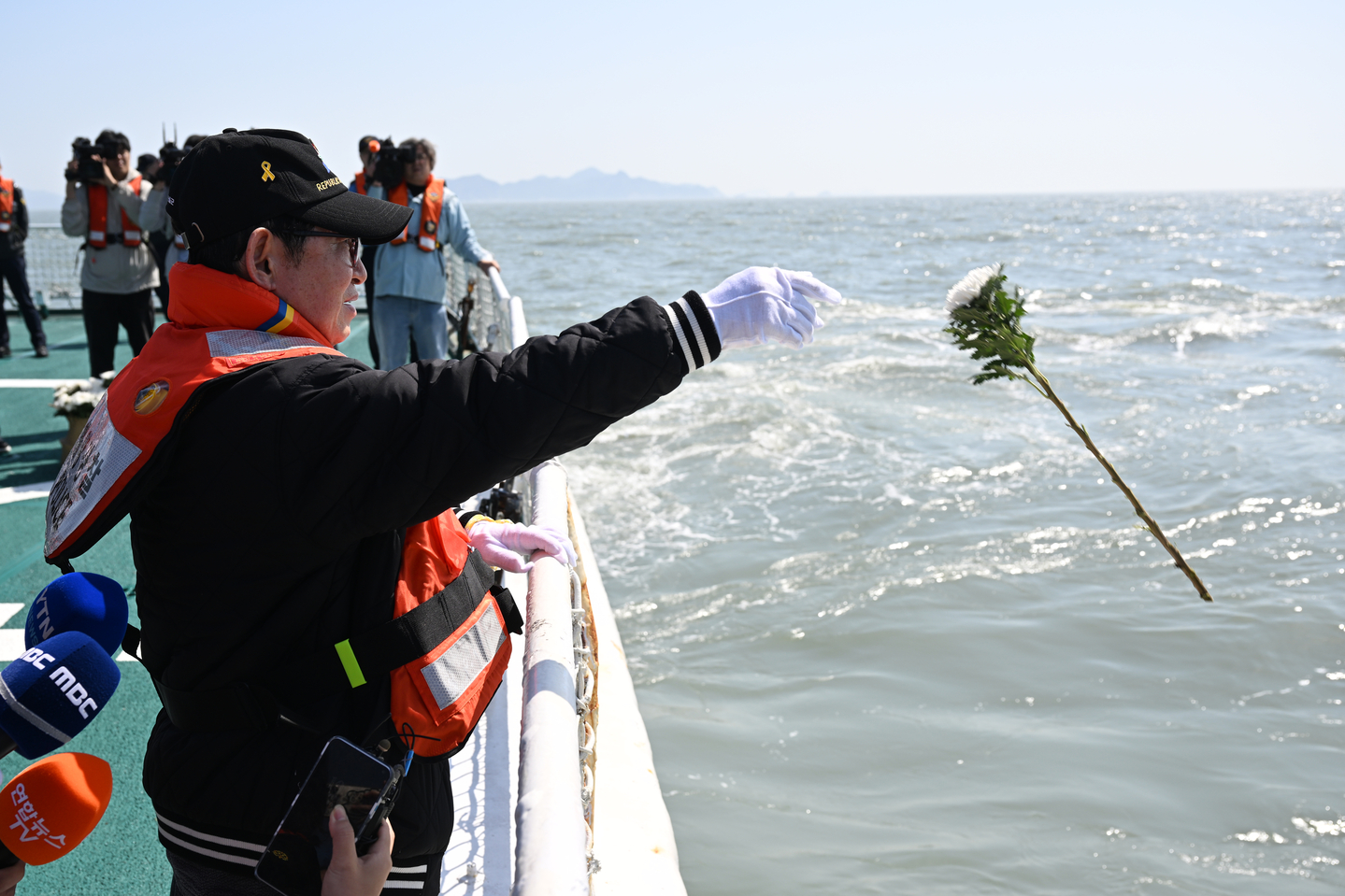 A bereaved family member of the Sewol ferry disaster throws a chrysanthemum into the sea at Jindo County, South Jeolla, on April 16. [YONHAP]