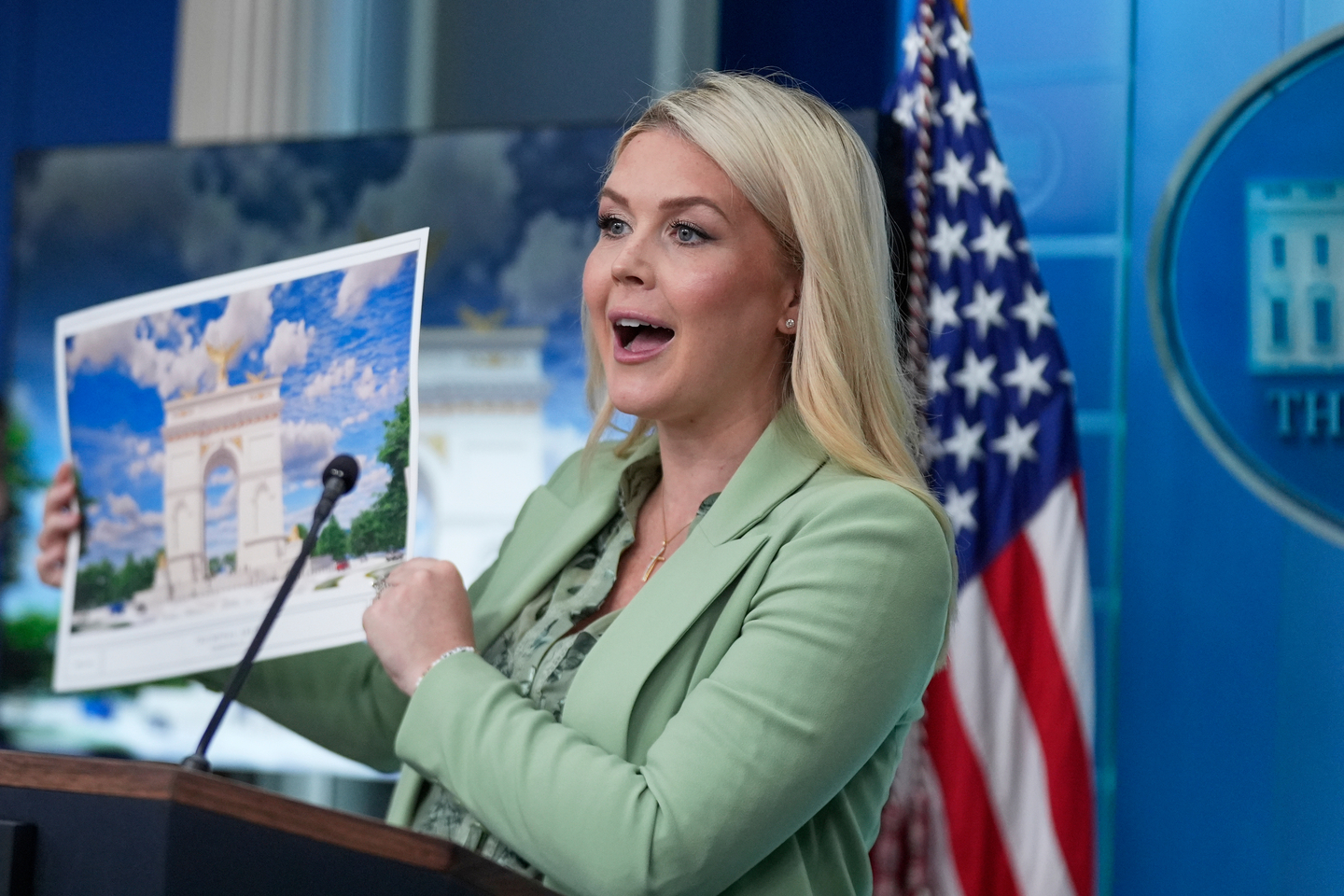 White House press secretary Karoline Leavitt holds up an artist rendering of the new triumphal arch as she speaks with reporters in the James Brady Press Briefing Room at the White House in Washington on April 15.[AP/YONHAP]