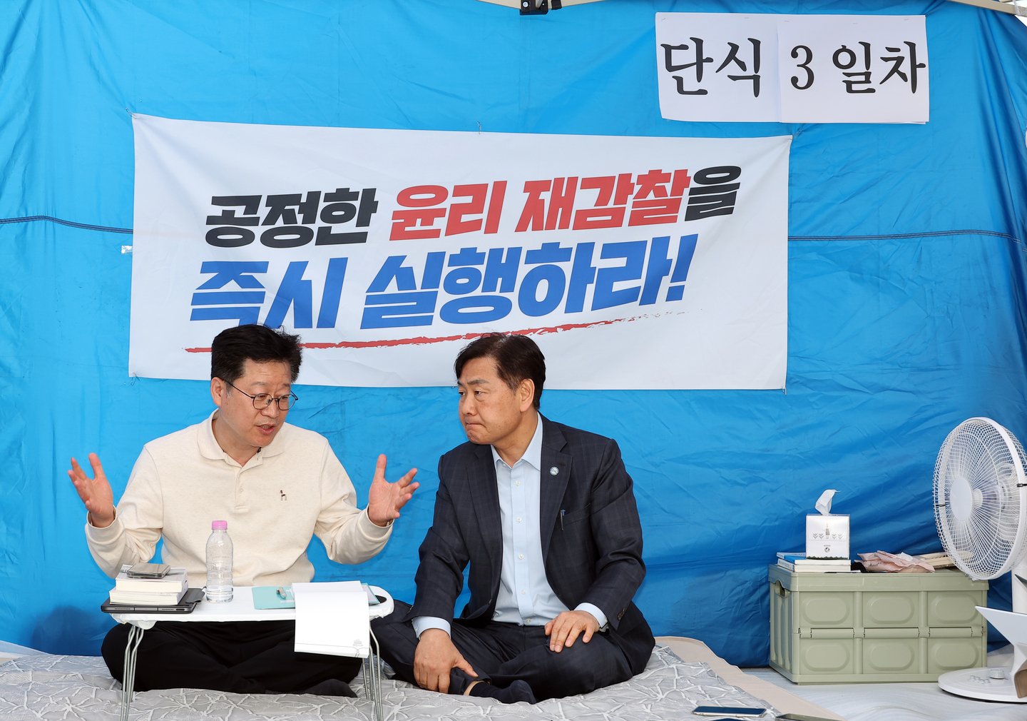 Rep. An Ho-young (left), who is on a hunger strike demanding a reinvestigation into allegations that a third party covered meal expenses after losing the North Jeolla gubernatorial primary to Rep. Lee Won-taeg, speaks with incumbent North Jeolla Gov. Kim Kwan-young at Ahn’s protest site in front of the National Assembly main building on April 13. [YONHAP]