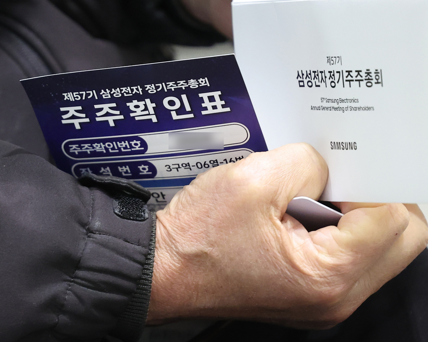 A Samsung Electronics shareholder holds verification papers to attend the company's general shareholders meeting in Suwon, Gyeonggi, on March 18. [JOINT PRESS CORPS]