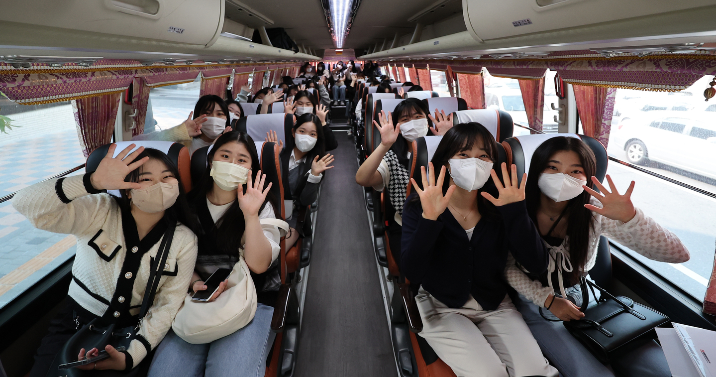 High school students wave on a bus during their field trip in May 2022. [YONHAP] 