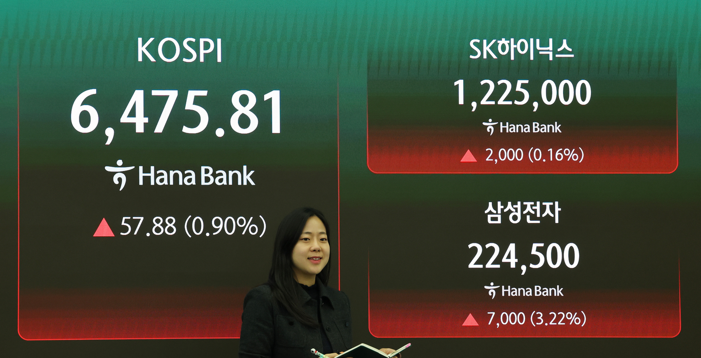 A trader walks by a screen displaying the Kospi at Hana Bank's dealing room in Jung District, central Seoul, on April 23. [YONHAP]