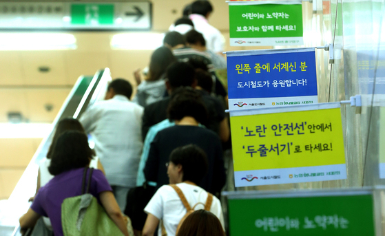 Small-sized flags are attached to the wall to inform people to stand in two lines on escalators at Seodaemun Station in western Seoul in 2013. [PARK JONG-KEUN]