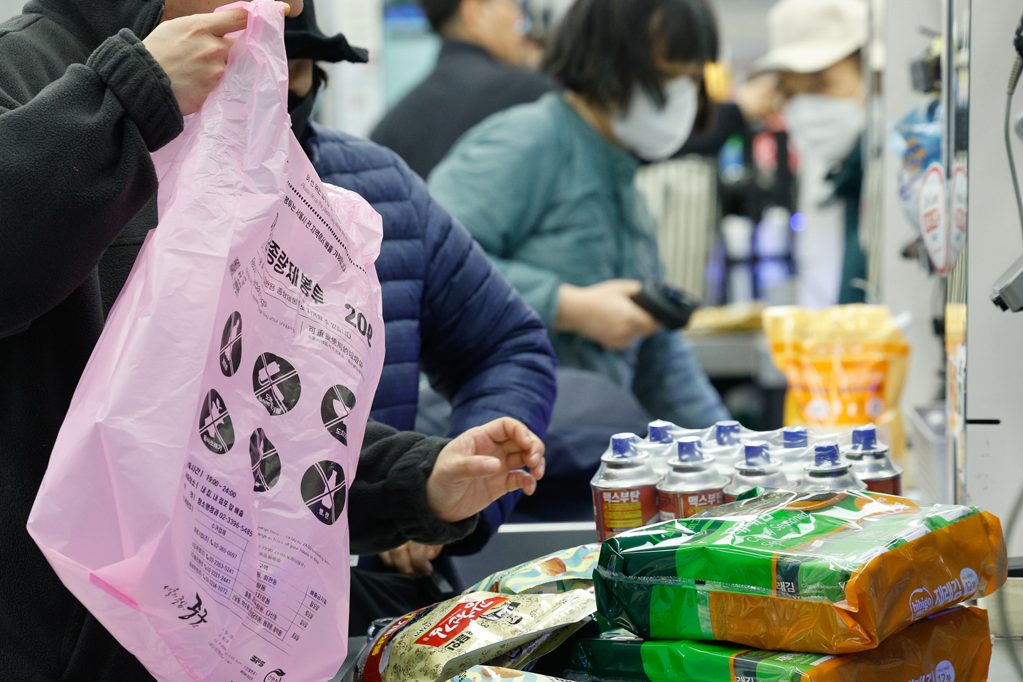 A customer puts groceries into a garbage bag, which is offered for bagging to be repurposed for trash disposal later, at a discount store in downtown Seoul on March 30. [NEWS1] 