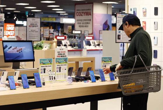 A customer looks at phones at a supermarket in Seoul on April 15. [NEWS1] 