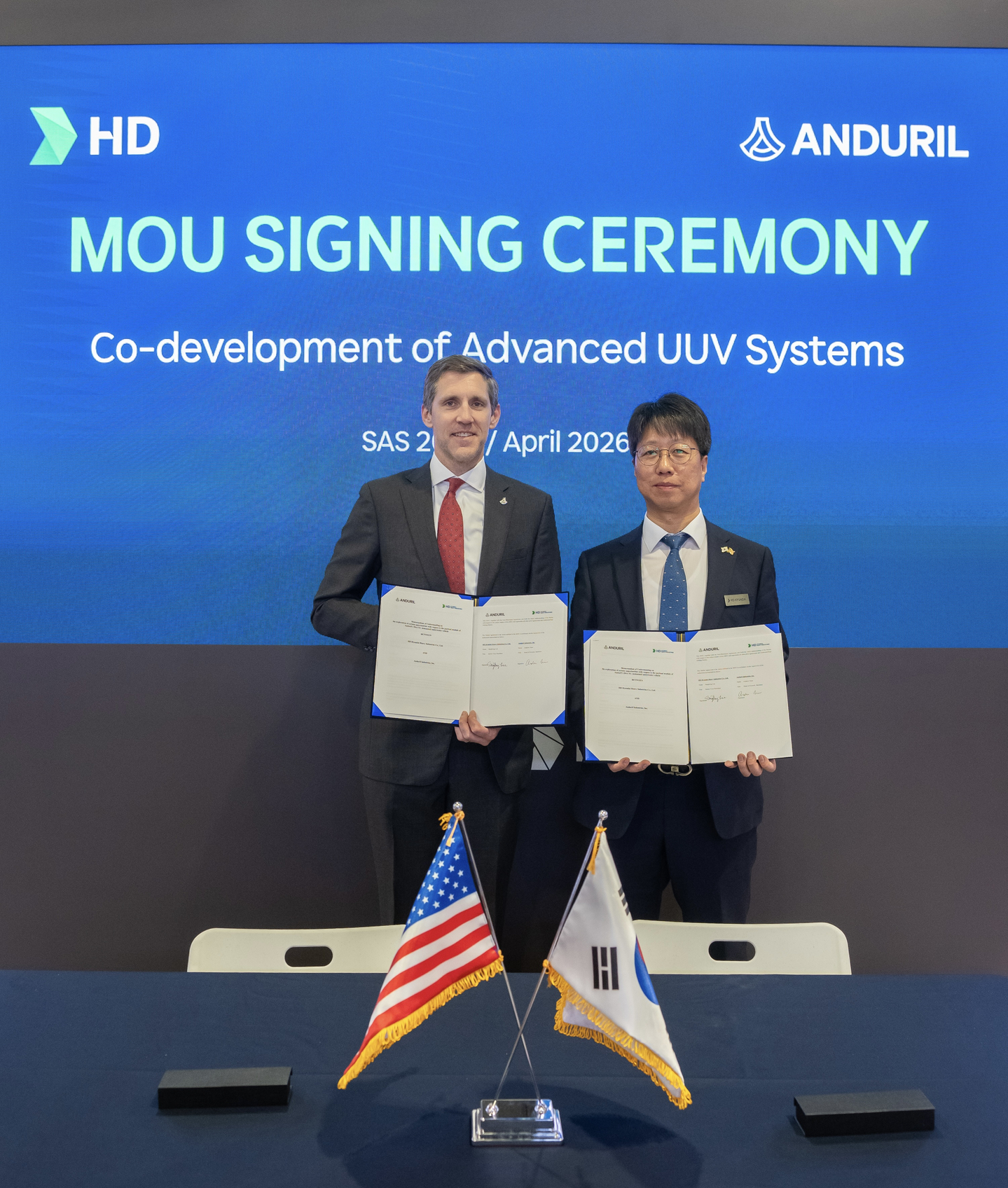 Lee Sang-bong, executive vice president and head of naval ship design division at HD Hyundai Heavy Industries, left, and Andrew Nuss, head of maritime at Anduril, pose for a photo after signing memorandum of understanding in the development of unmanned underwater vehicles at the Sea, Air and Space Exposition 2026 in Washington D.C. on April 22. [HD HYUNDAI]
