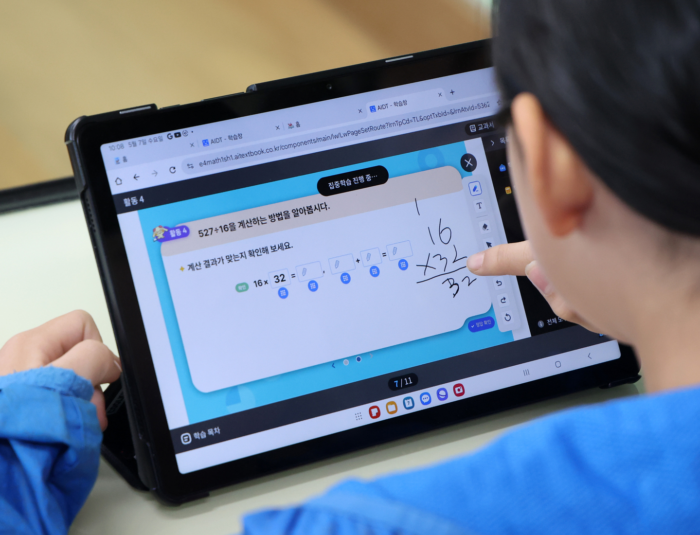 A student at Namsan Elementary School in Chuncheon, Gangwon, solves math division problems using an AI Digital Textbook during an open class showcasing the newly rolled-out digital curriculum on May 7, 2025. [YONHAP]