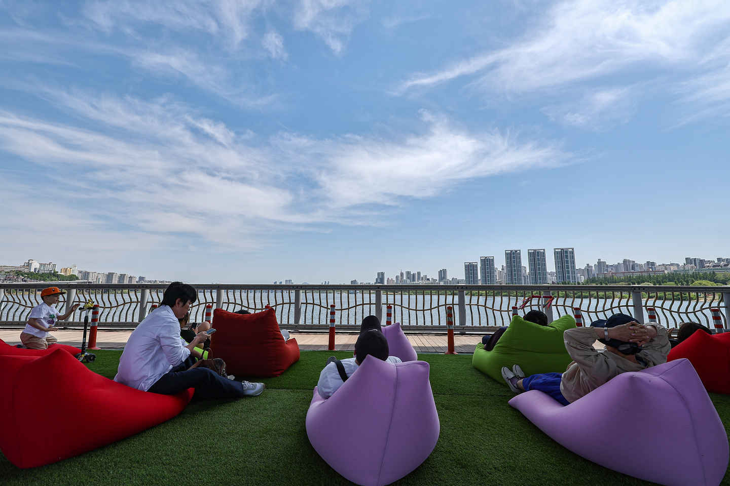 People relax along Jamsu Bridge in Seocho District, southern Seoul, as the 2026 car-free Jamsu Bridge walking festival takes place on April 26, with temperatures hovering around 25 degrees Celsius (77 degrees Fahrenheit) and early summer weather settling over the city. [NEWS1]