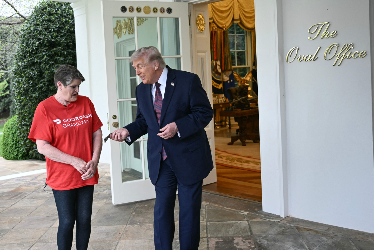 U.S. President Donald Trump tips Doordash delivery worker Sharon Simmons after she delivered McDonald's outside of the Oval Office at the White House in Washington on April 13. [AFP/YONHAP]