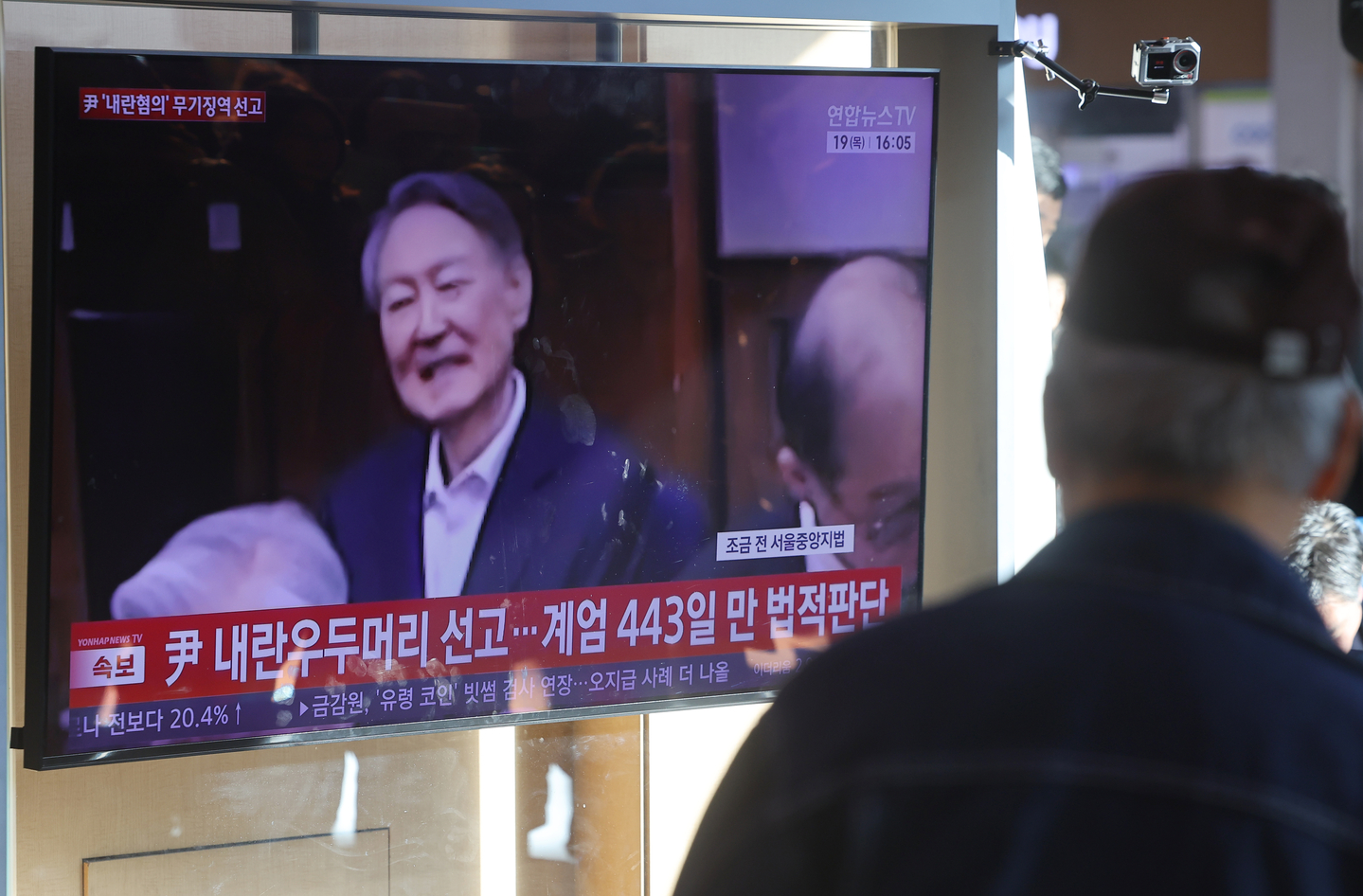 This file photo, taken Feb. 19 shows a person watching a news report of former President Yoon Suk Yeol's conviction on charges of leading an insurrection through his failed 2024 martial law bid aired in a live broadcast at Seoul Station in Jung District, central Seoul. [YONHAP] 