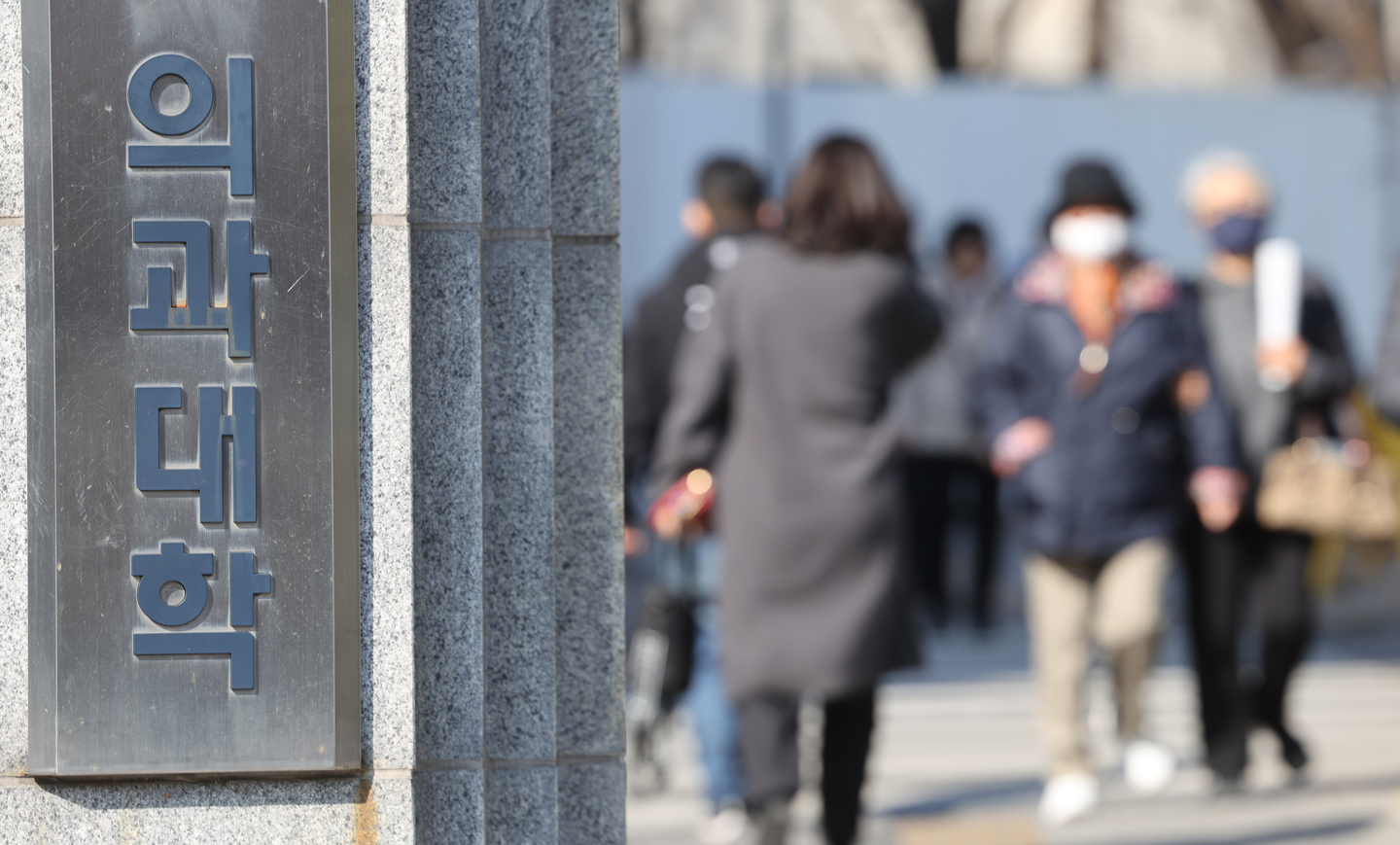 Pedestrians pass by near a medical school in Seoul on the March 13. [YONHAP]