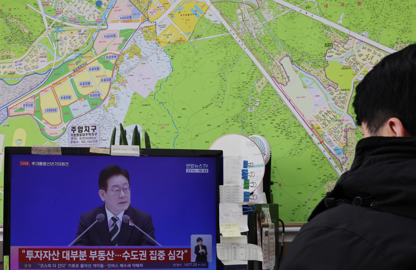 An employee at a real estate agency in Seocho District, southern Seoul, watches a broadcast of President Lee Jae Myung’s New Year press conference on Jan. 21. [YONHAP]