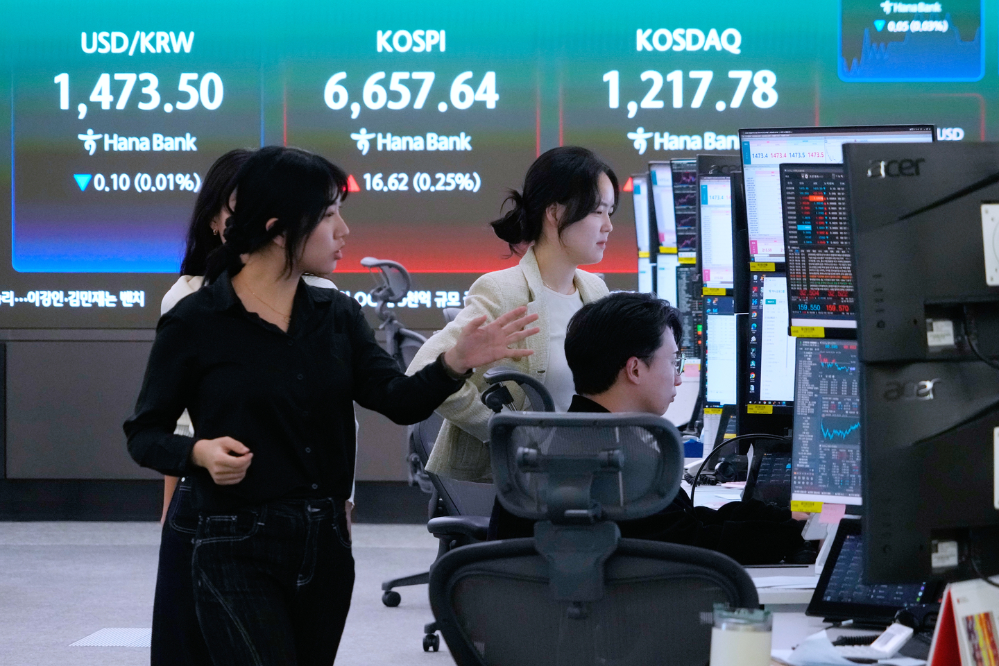Currency traders work near a screen showing the Kospi and the dollar-won exchange rate at the foreign exchange trading room of the Hana Bank headquarters in central Seoul on April 29. [AP/YONHAP]