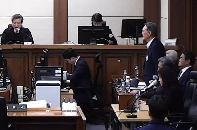 Former President Yoon Suk Yeol, who is charged with offenses including obstruction of official duties and abuse of authority, stands to hear the verdict during his appellate sentencing hearing at the Seoul High Court in Seocho District, southern Seoul, on April 29. [SCREEN CAPTURE]