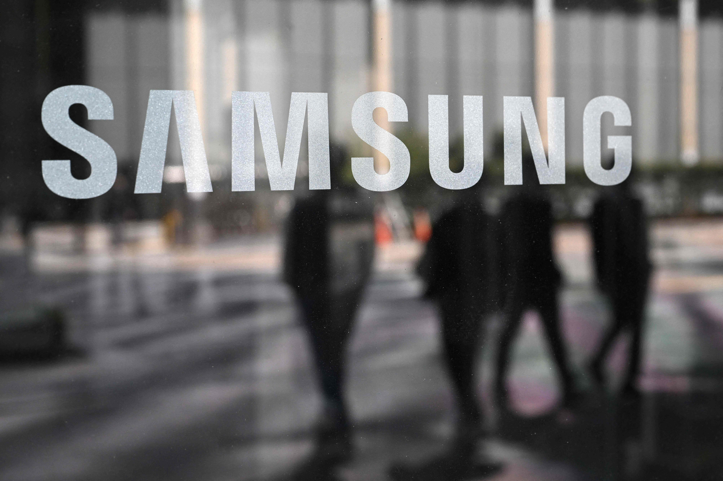People walk past the Samsung logo displayed on a glass door at the company's Seocho building in Seoul on April 30, 2025. [AFP/YONHAP]