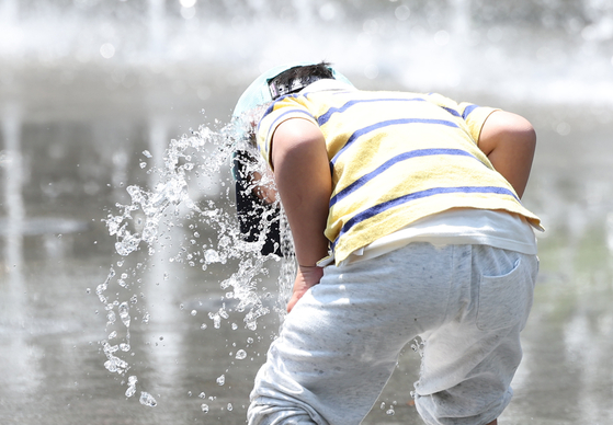 A kid plays at the water fountain in Gwanghwamun Square in central Seoul on April 30. [NEWS1] 